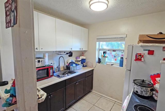 kitchen with sink, white cabinets, white refrigerator, a textured ceiling, and light tile patterned floors