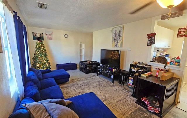 living room featuring ceiling fan and a textured ceiling