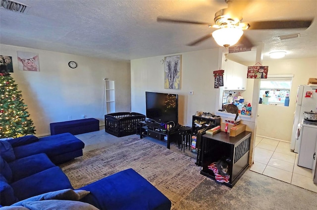 living room with ceiling fan, light tile patterned floors, and a textured ceiling