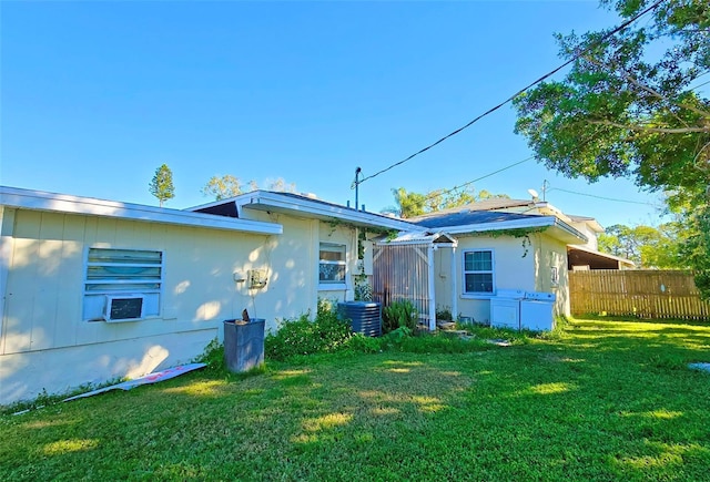 rear view of property with a yard and central air condition unit