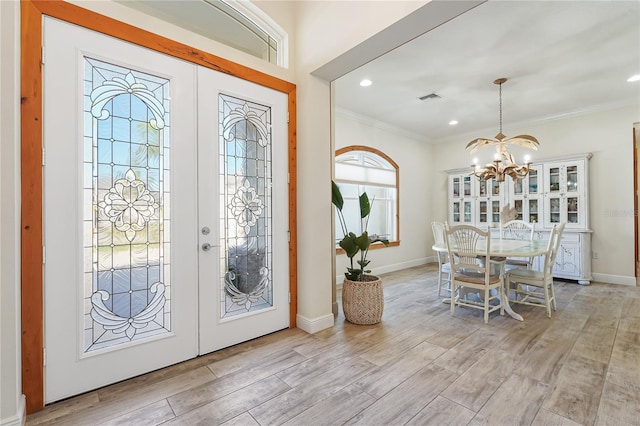 foyer entrance featuring a chandelier, french doors, and ornamental molding