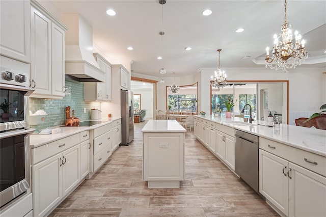 kitchen featuring white cabinetry, hanging light fixtures, stainless steel appliances, premium range hood, and a kitchen island