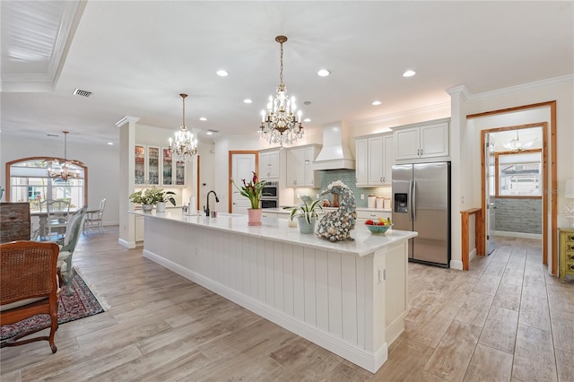 kitchen featuring premium range hood, a spacious island, stainless steel fridge, and pendant lighting