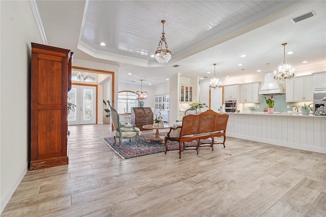 sitting room featuring a tray ceiling, crown molding, french doors, and light hardwood / wood-style flooring