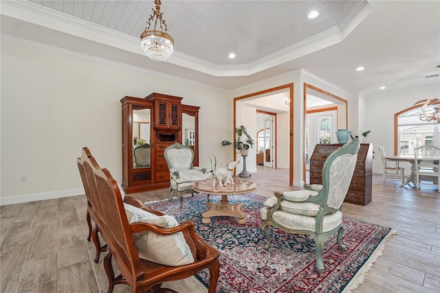 sitting room featuring a raised ceiling, ornamental molding, light hardwood / wood-style flooring, and an inviting chandelier