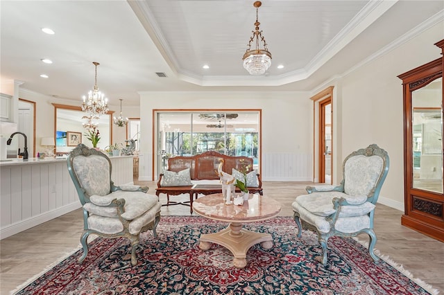 sitting room with a raised ceiling, crown molding, sink, a notable chandelier, and light hardwood / wood-style floors