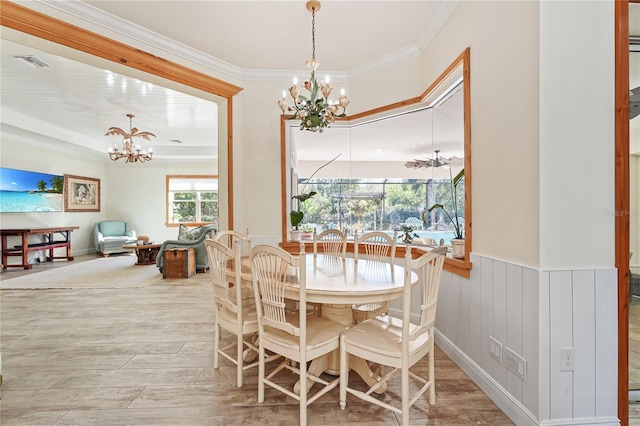 dining area with light hardwood / wood-style flooring, ornamental molding, and an inviting chandelier