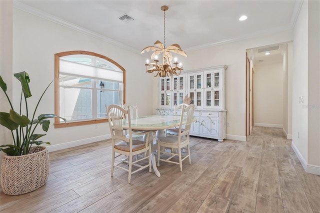 dining room with a notable chandelier, light wood-type flooring, and ornamental molding