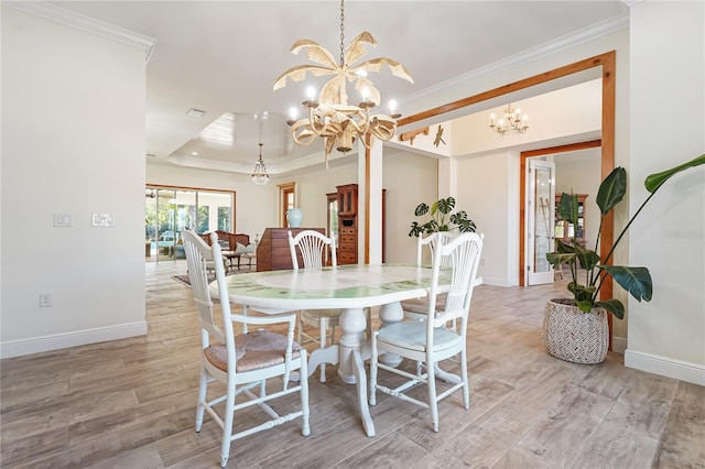 dining space with light hardwood / wood-style floors, a raised ceiling, ornamental molding, and a chandelier