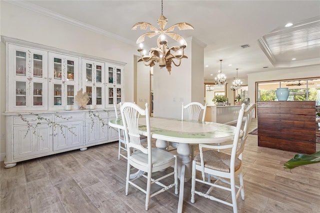 dining space with light wood-type flooring, ornamental molding, and an inviting chandelier