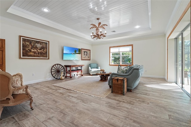 living room with light wood-type flooring, a tray ceiling, crown molding, and a notable chandelier