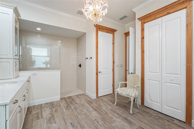 bathroom featuring a tile shower, vanity, crown molding, and wood-type flooring