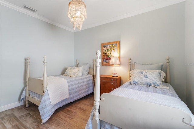 bedroom featuring hardwood / wood-style flooring, a notable chandelier, and crown molding