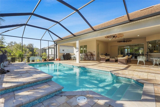 view of pool featuring a patio area, ceiling fan, outdoor lounge area, and glass enclosure