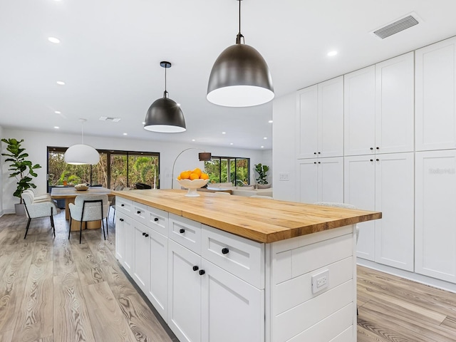 kitchen with white cabinets, butcher block counters, and hanging light fixtures