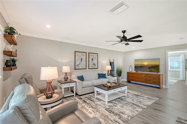 living room with ceiling fan, light wood-type flooring, and ornamental molding