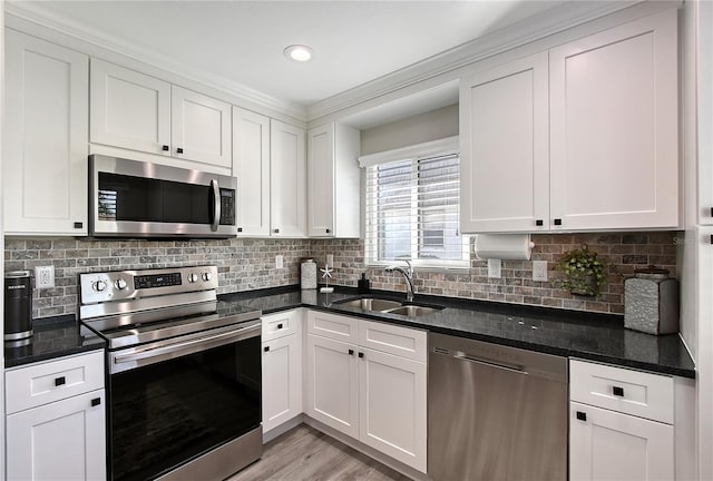 kitchen featuring a sink, dark stone counters, white cabinetry, and stainless steel appliances