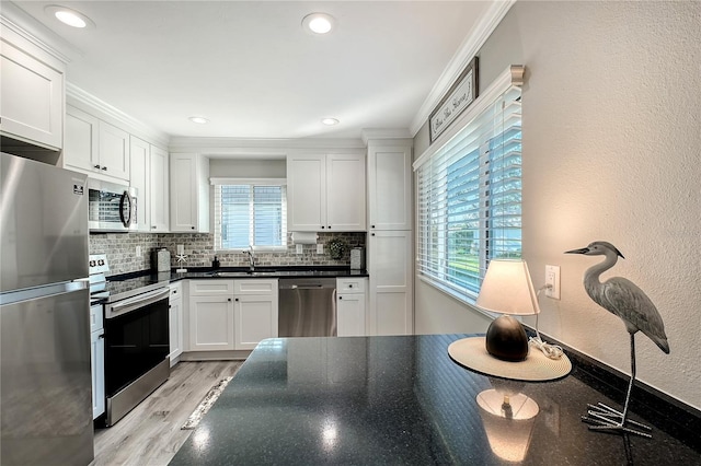 kitchen with backsplash, white cabinetry, a healthy amount of sunlight, and appliances with stainless steel finishes