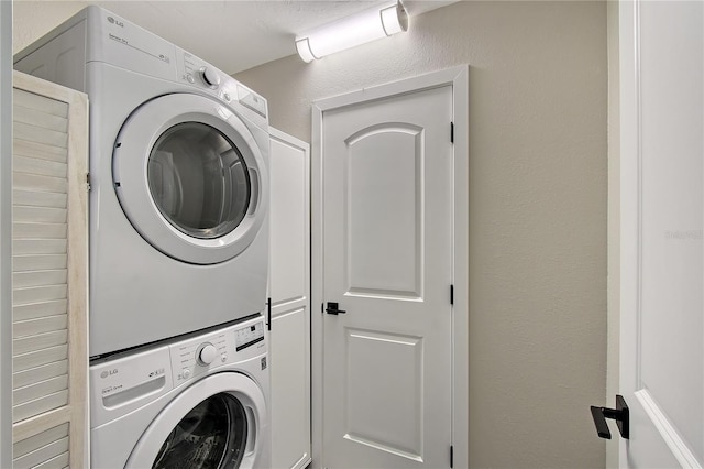 laundry area with cabinets and stacked washer / dryer