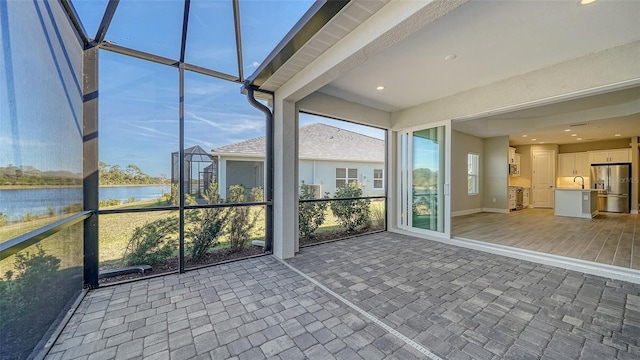 unfurnished sunroom with sink and a water view