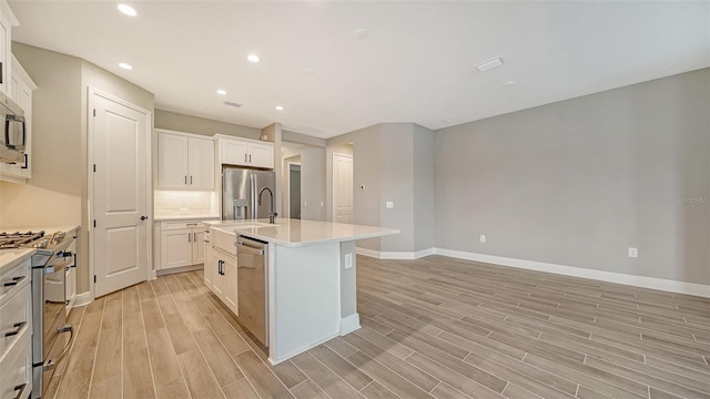 kitchen with white cabinetry, a center island with sink, light hardwood / wood-style flooring, and appliances with stainless steel finishes