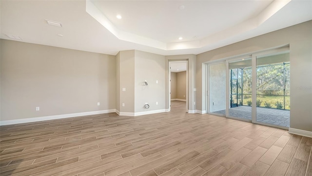 unfurnished room with light hardwood / wood-style floors and a tray ceiling