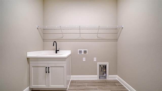 laundry area featuring electric dryer hookup, hookup for a washing machine, light hardwood / wood-style flooring, and sink