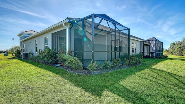 view of side of home with central AC unit, glass enclosure, and a yard