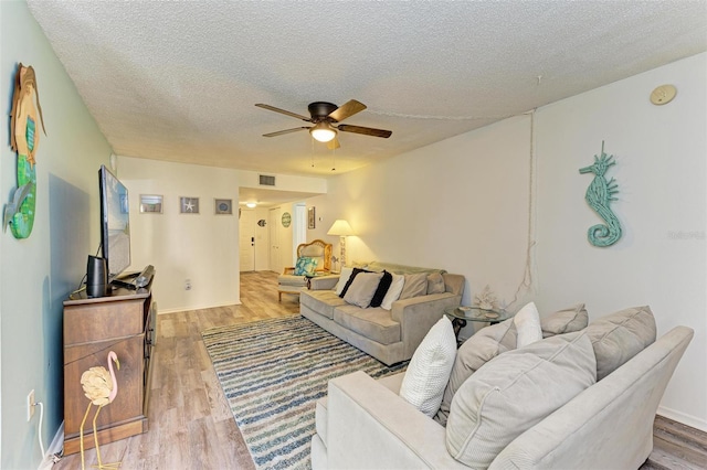 living room featuring hardwood / wood-style floors, a textured ceiling, and ceiling fan