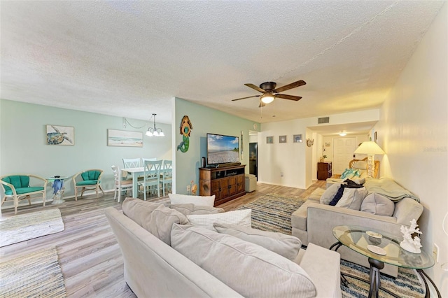 living room with a textured ceiling, ceiling fan with notable chandelier, and light wood-type flooring