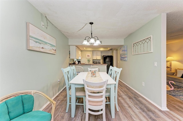 dining room with a notable chandelier, light hardwood / wood-style floors, and a textured ceiling