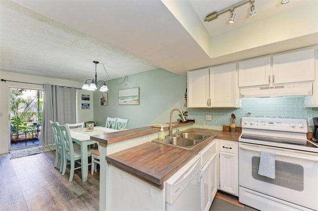 kitchen with sink, kitchen peninsula, decorative light fixtures, white appliances, and white cabinets