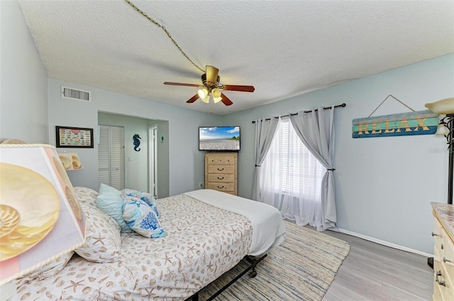 bedroom with hardwood / wood-style flooring, ceiling fan, and a textured ceiling