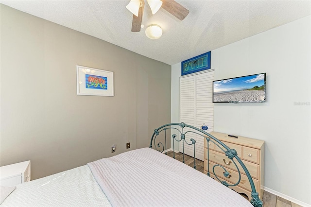 bedroom with ceiling fan, hardwood / wood-style floors, and a textured ceiling