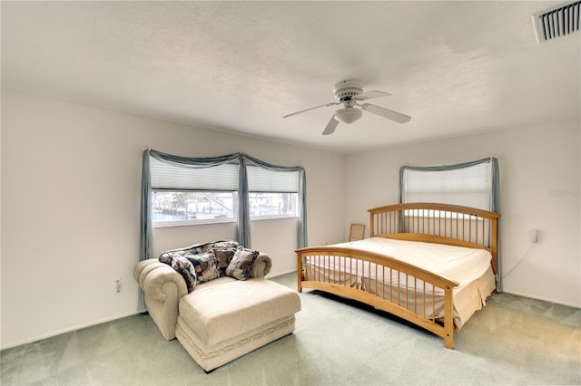 carpeted bedroom featuring ceiling fan and a textured ceiling