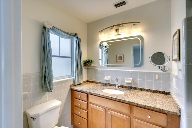 bathroom with vanity, toilet, and tile walls