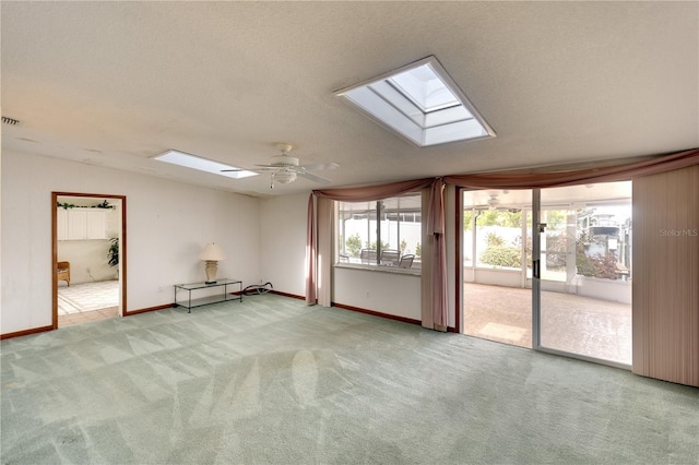 carpeted empty room with a textured ceiling, a skylight, and ceiling fan