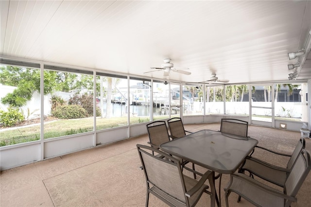 sunroom / solarium with ceiling fan and a water view