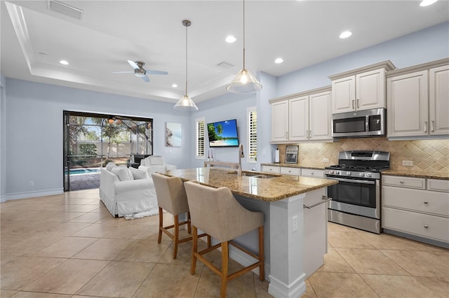 kitchen featuring a raised ceiling, sink, stainless steel appliances, and stone countertops