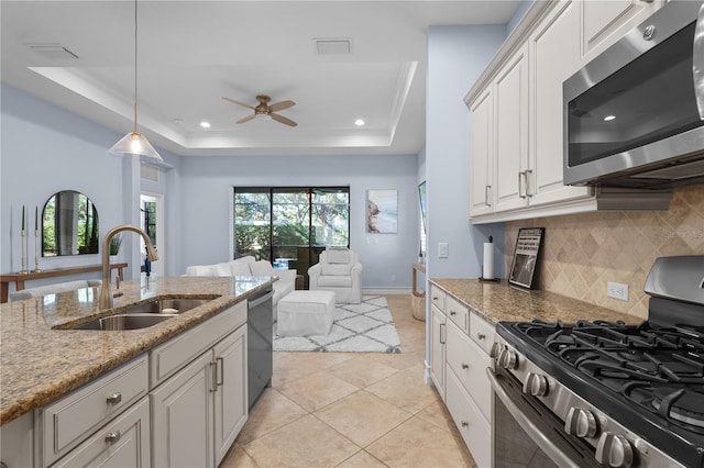 kitchen featuring stainless steel appliances, a tray ceiling, sink, white cabinets, and hanging light fixtures