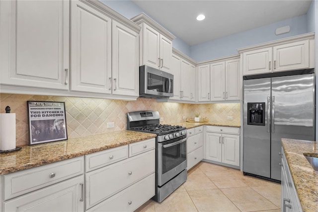 kitchen featuring light tile patterned flooring, light stone counters, white cabinetry, and appliances with stainless steel finishes