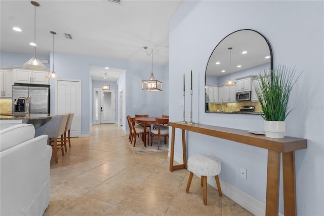 interior space with white cabinetry, stainless steel appliances, and hanging light fixtures