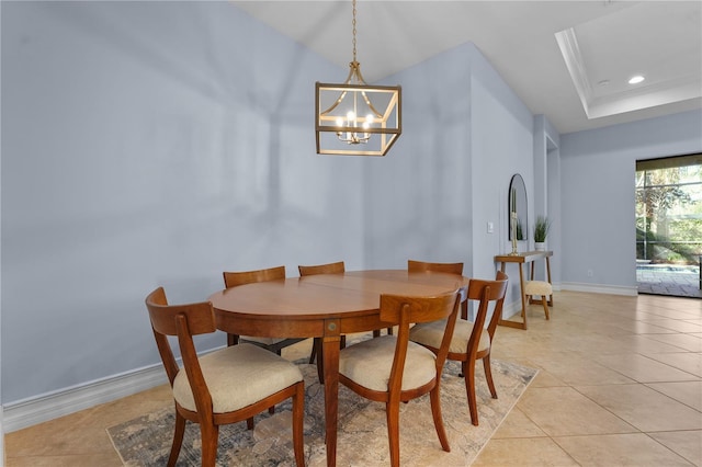 dining space with a notable chandelier, light tile patterned flooring, and a raised ceiling