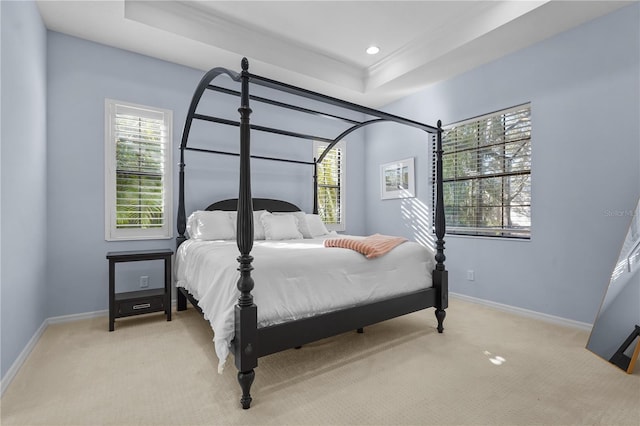 bedroom with a raised ceiling and light colored carpet