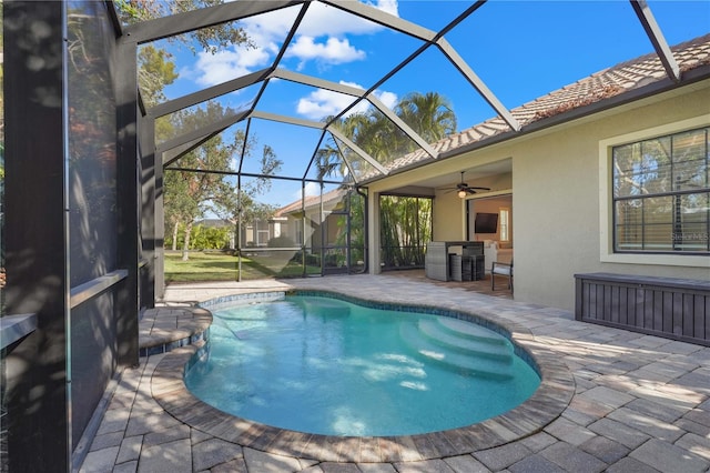 view of pool with glass enclosure, ceiling fan, and a patio