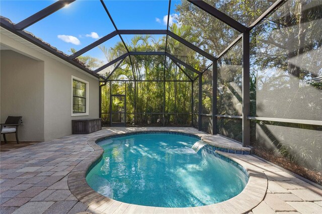 view of pool featuring pool water feature, glass enclosure, and a patio area