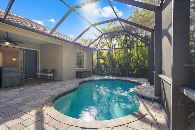 view of pool with glass enclosure, ceiling fan, and a patio