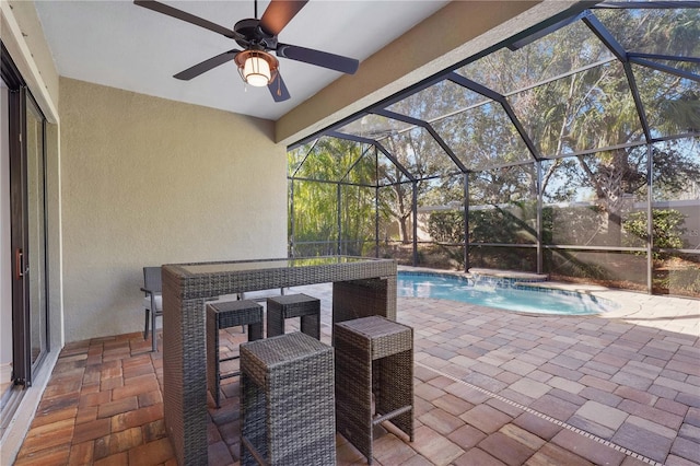 view of patio with a hot tub, glass enclosure, and ceiling fan