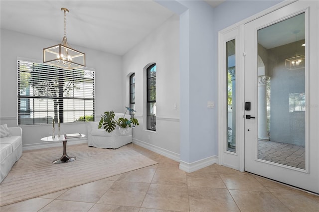 foyer entrance featuring a chandelier, baseboards, and light tile patterned floors