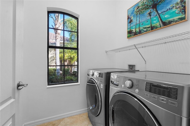 clothes washing area featuring laundry area, washing machine and dryer, light tile patterned floors, and baseboards